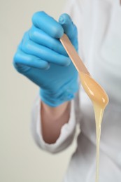 Woman in gloves holding spatula with hot depilatory wax, closeup Photo of Woman in gloves holding spatula with hot depilatory wax, closeup
