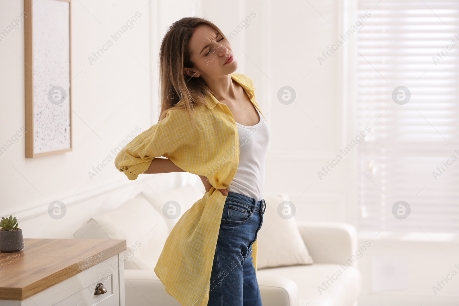 Woman suffering from back pain at home. Symptom of bad posture Photo of Woman suffering from back pain at home. Symptom of bad posture