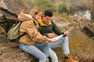 Couple of travelers with backpacks and map on rocky mountain. Autumn vacation Photo of Couple of travelers with backpacks and map on rocky mountain. Autumn vacation