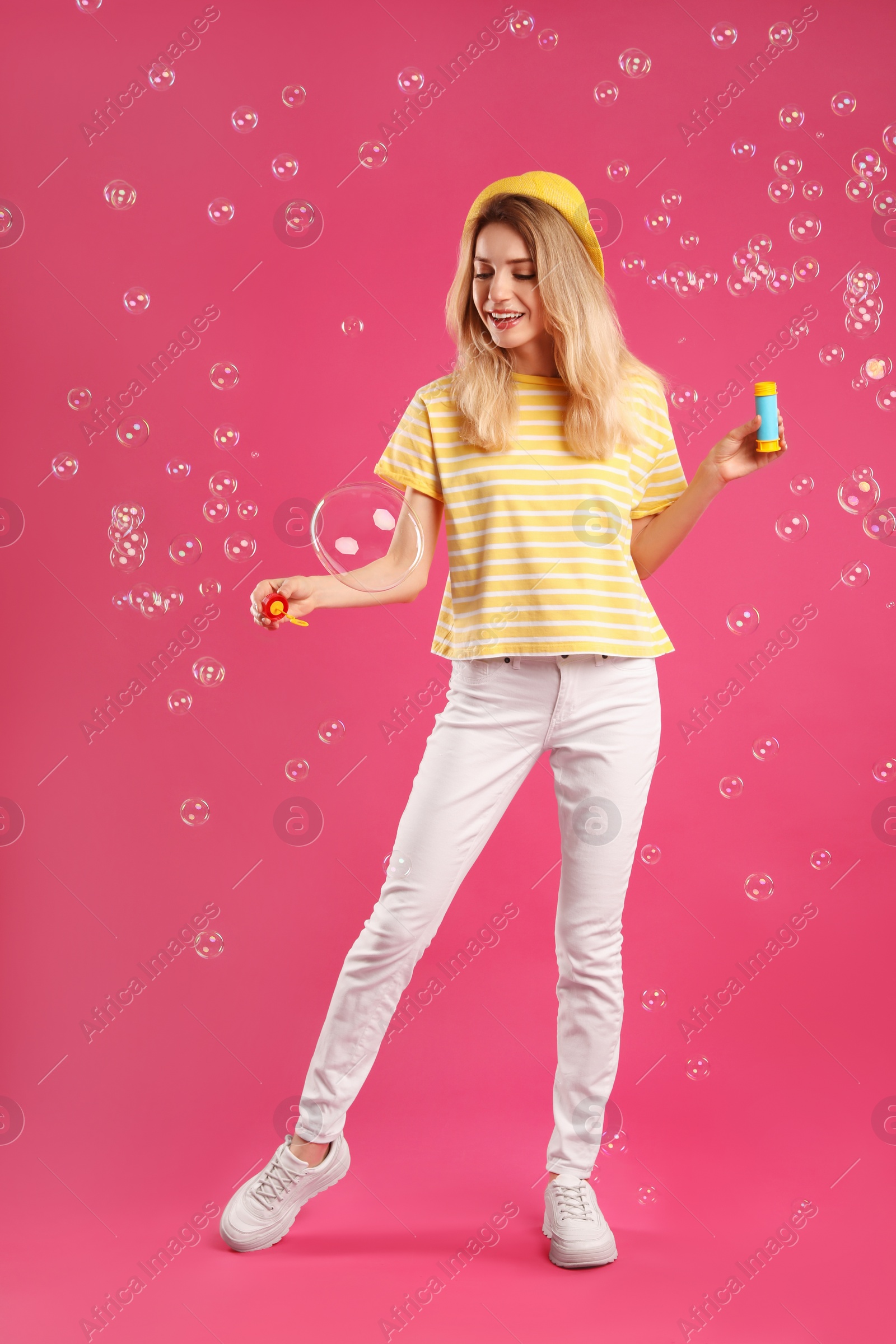 Young woman blowing soap bubbles on pink background Photo of Young woman blowing soap bubbles on pink background