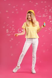 Young woman blowing soap bubbles on pink background Photo of Young woman blowing soap bubbles on pink background