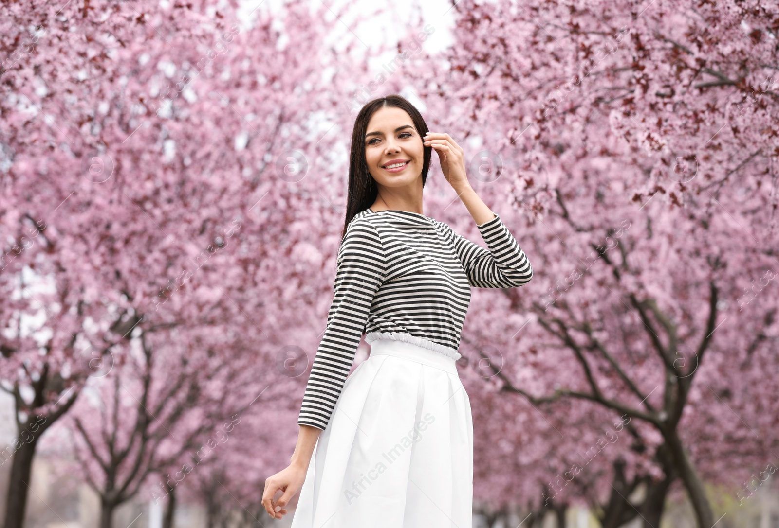 Pretty young woman in park with blooming trees. Spring look Photo of Pretty young woman in park with blooming trees. Spring look