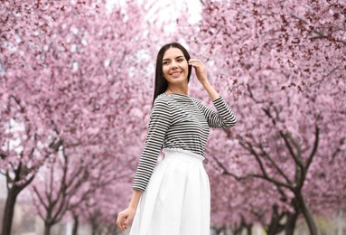 Pretty young woman in park with blooming trees. Spring look Photo of Pretty young woman in park with blooming trees. Spring look