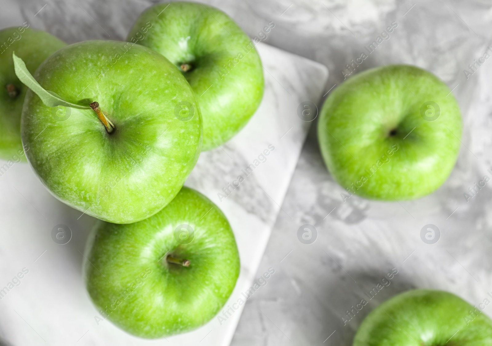 Marble board with fresh green apples on table, top view Photo of Marble board with fresh green apples on table, top view