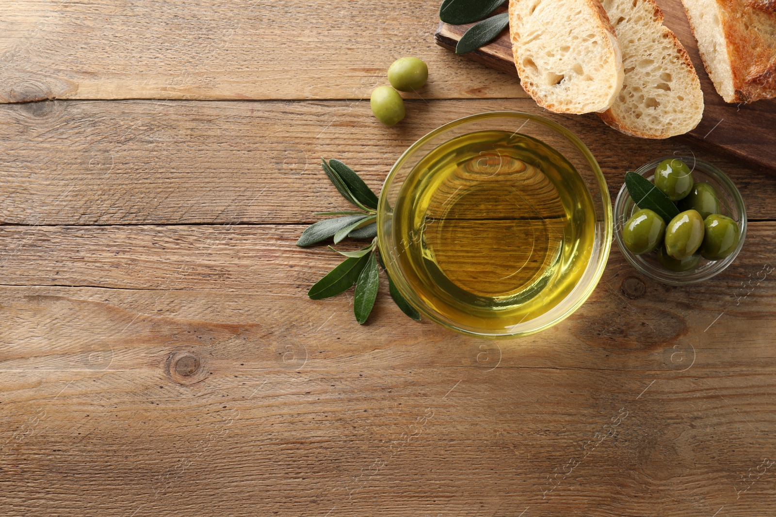 Glass bowl of oil, ripe olives and bread on wooden table, flat lay. Space for text Photo of Glass bowl of oil, ripe olives and bread on wooden table, flat lay. Space for text