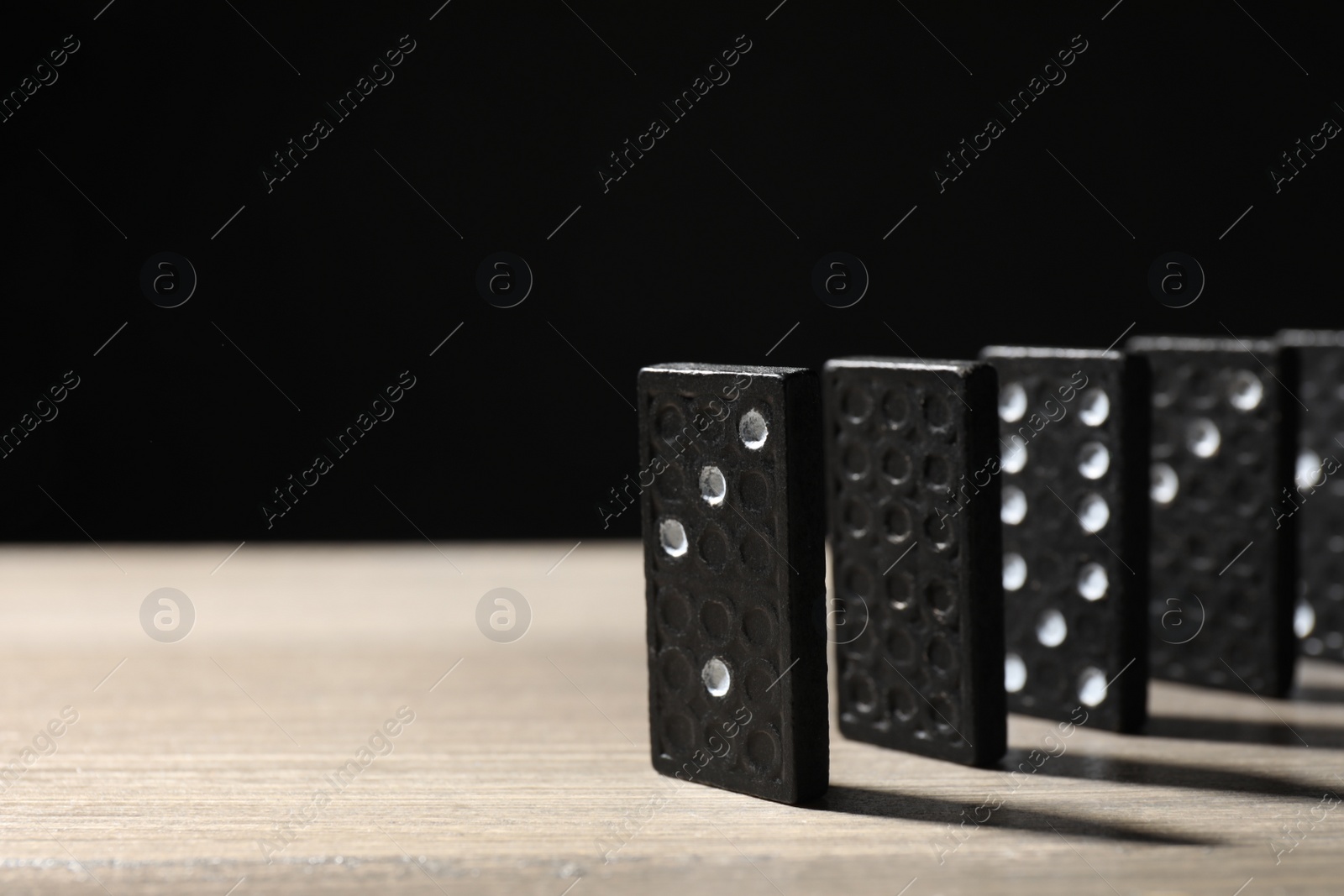 Domino tiles on wooden table against black background. Space for text Photo of Domino tiles on wooden table against black background. Space for text