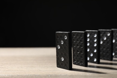Domino tiles on wooden table against black background. Space for text Photo of Domino tiles on wooden table against black background. Space for text