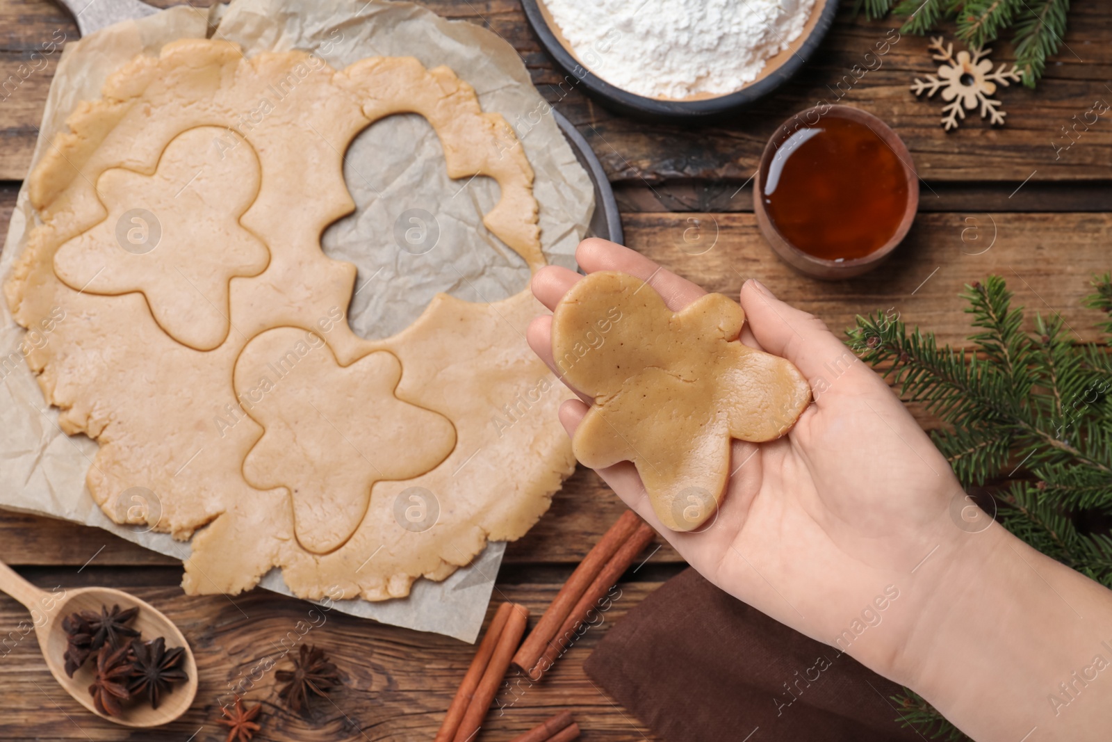 Making homemade Christmas cookies. Woman holding gingerbread man above wooden table, top view Photo of Making homemade Christmas cookies. Woman holding gingerbread man above wooden table, top view