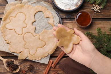 Making homemade Christmas cookies. Woman holding gingerbread man above wooden table, top view Photo of Making homemade Christmas cookies. Woman holding gingerbread man above wooden table, top view
