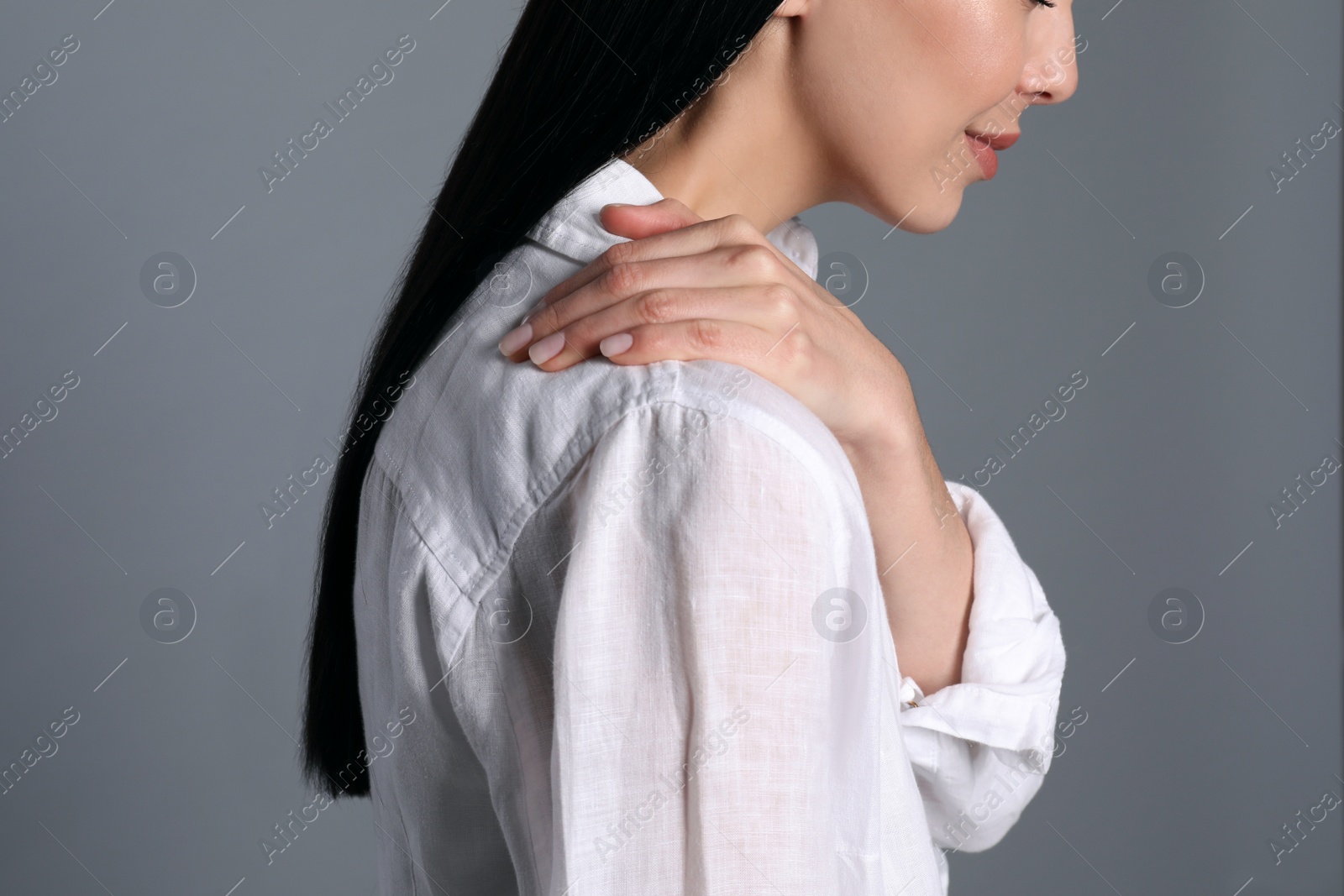 Woman suffering from shoulder pain on grey background, closeup Photo of Woman suffering from shoulder pain on grey background, closeup