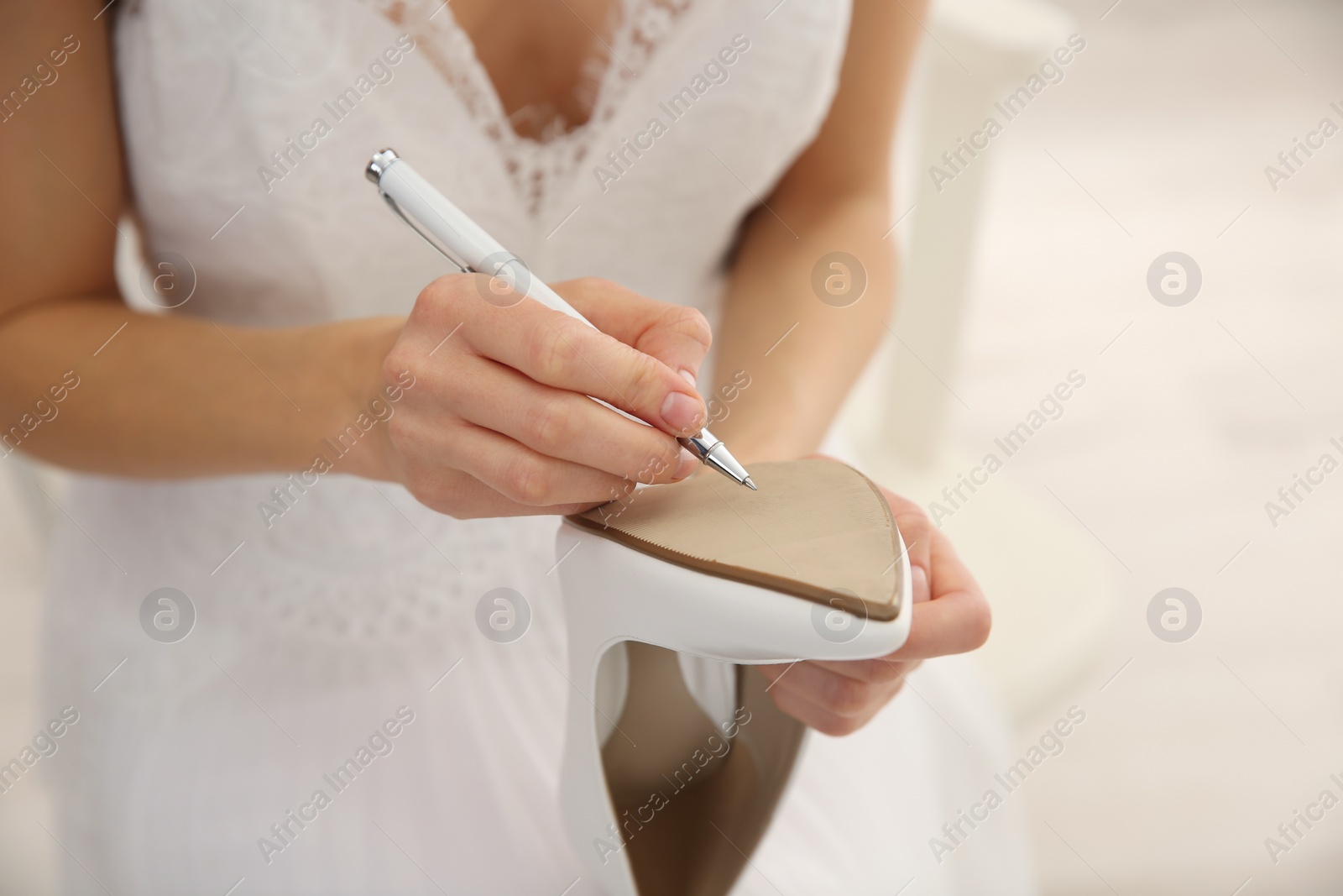 Young bride writing on her shoe indoors, closeup. Wedding superstition Photo of Young bride writing on her shoe indoors, closeup. Wedding superstition