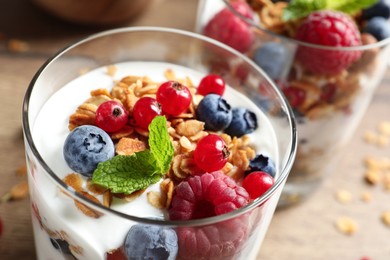 Tasty dessert with yogurt, berries and granola on wooden table, closeup Image of Tasty dessert with yogurt, berries and granola on wooden table, closeup