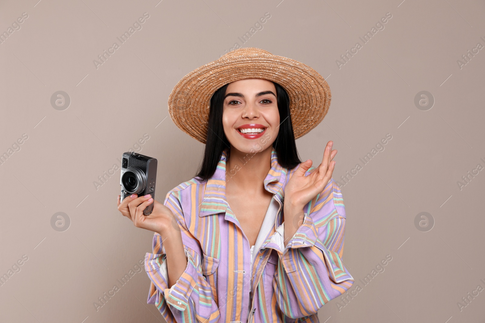 Photo of Beautiful young woman with straw hat and camera on beige background