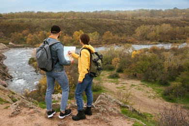 Couple of travelers with backpacks and map planning trip in mountains, back view. Autumn vacation Photo of Couple of travelers with backpacks and map planning trip in mountains, back view. Autumn vacation