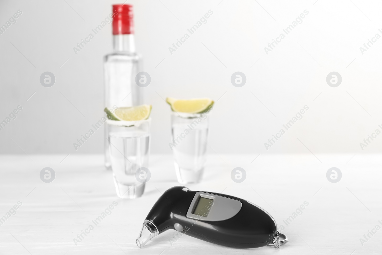 Modern breathalyzer and alcohol on white table. Space for text Photo of Modern breathalyzer and alcohol on white table. Space for text