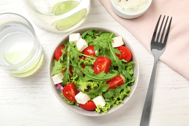 Delicious salad with arugula and vegetables on white table, flat lay Photo of Delicious salad with arugula and vegetables on white table, flat lay