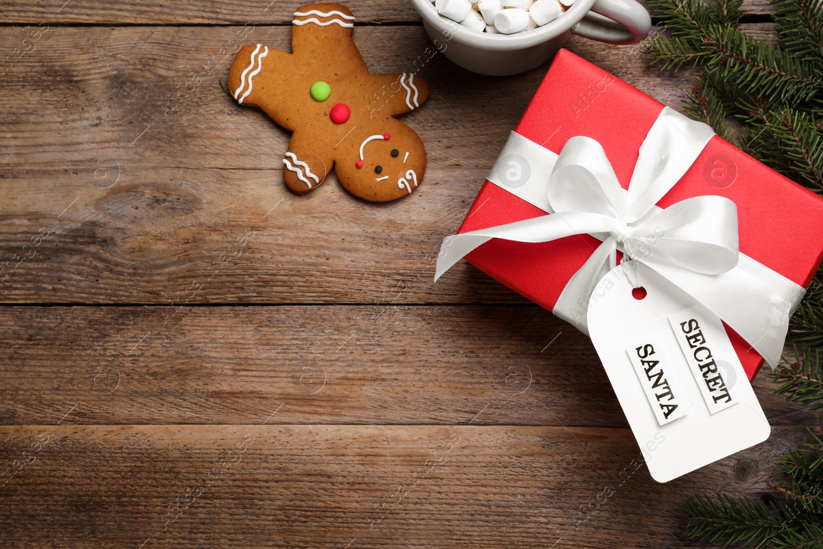 Flat lay composition with present from secret Santa on wooden table, space for text Photo of Flat lay composition with present from secret Santa on wooden table, space for text