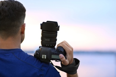 Photographer with professional camera near river at sunset, closeup Photo of Photographer with professional camera near river at sunset, closeup