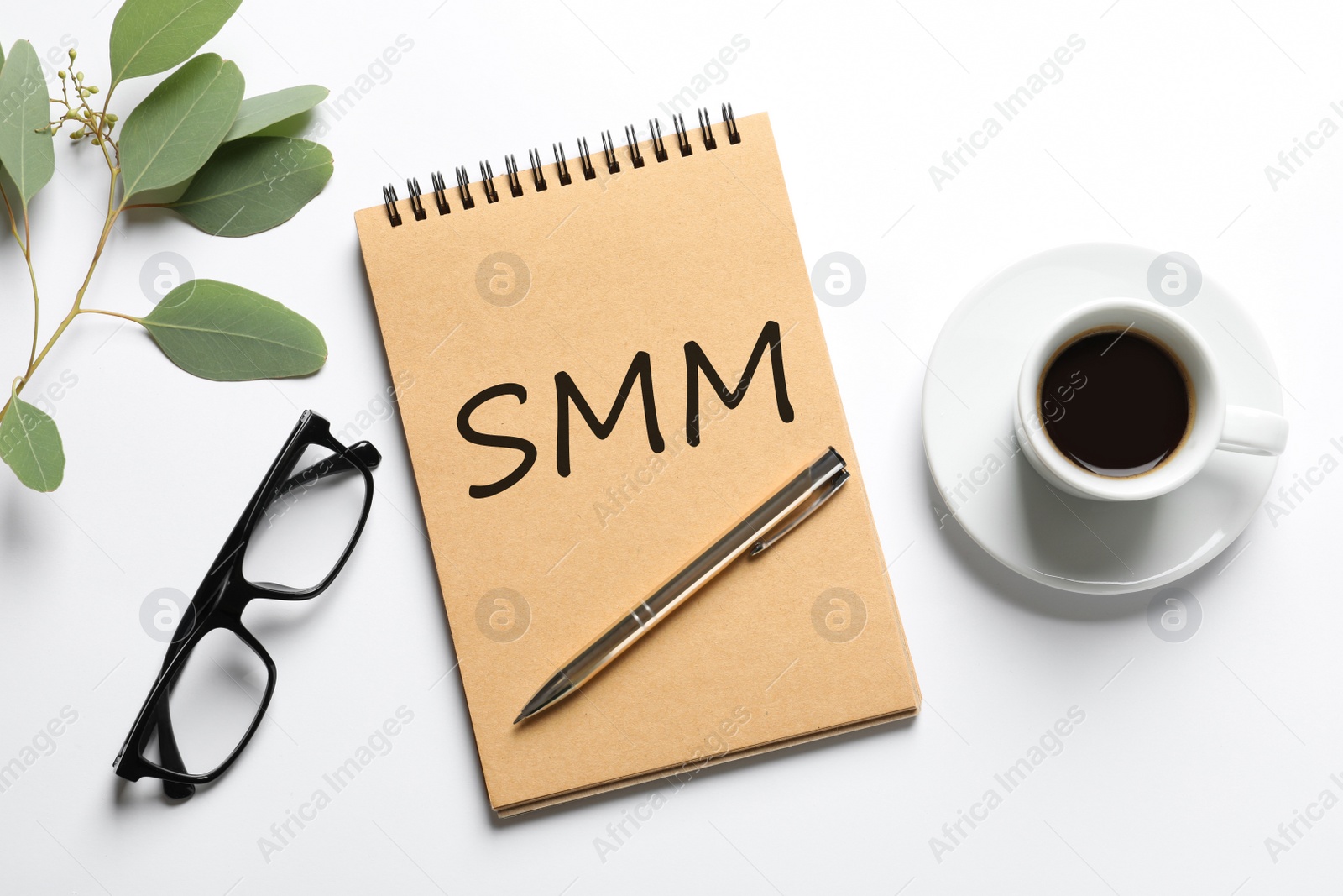 Notebook with abbreviation SMM, cup of coffee and glasses on white background, flat lay. Social media marketing Image of Notebook with abbreviation SMM, cup of coffee and glasses on white background, flat lay. Social media marketing