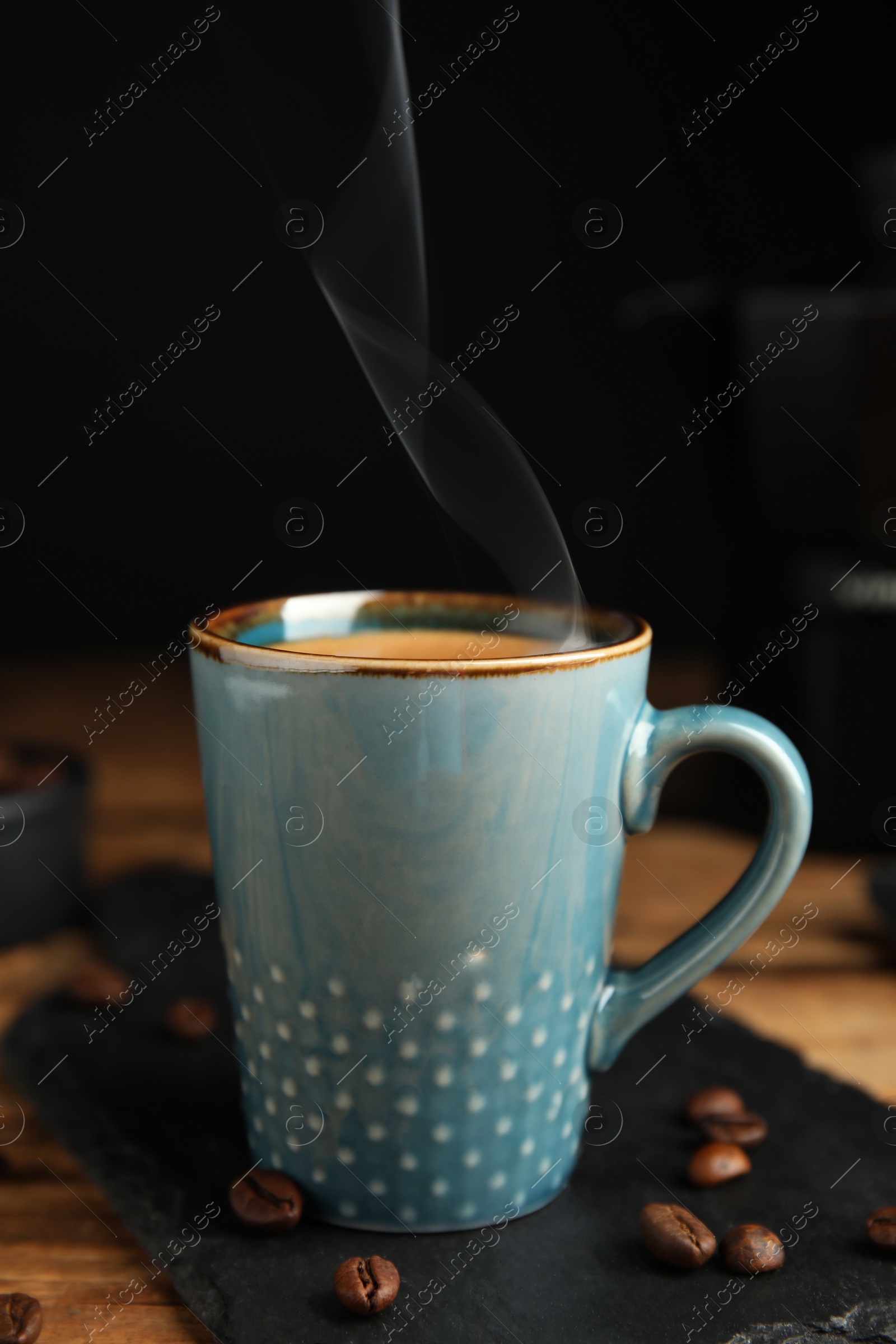 Photo of Cup of tasty coffee and beans on wooden table
