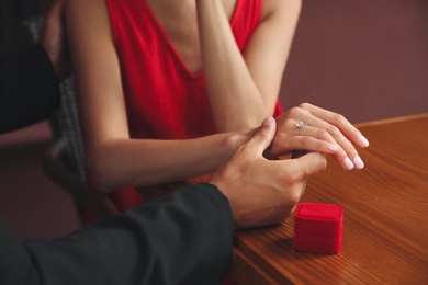 Man with engagement ring making proposal to his girlfriend at table, closeup Photo of Man with engagement ring making proposal to his girlfriend at table, closeup