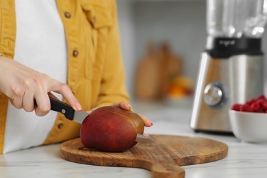 Woman preparing mango for tasty smoothie at white marble table in kitchen, closeup Photo of Woman preparing mango for tasty smoothie at white marble table in kitchen, closeup