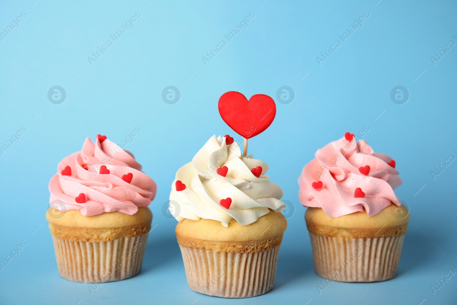 Tasty cupcakes for Valentine's Day on light blue background Photo of Tasty cupcakes for Valentine's Day on light blue background