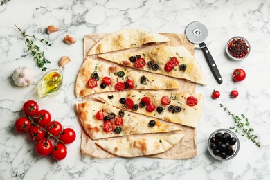 Delicious focaccia bread with olives and tomatoes on white marble table, flat lay Photo of Delicious focaccia bread with olives and tomatoes on white marble table, flat lay