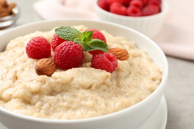 Tasty oatmeal porridge with raspberries and almond nuts in bowl on table, closeup Photo of Tasty oatmeal porridge with raspberries and almond nuts in bowl on table, closeup