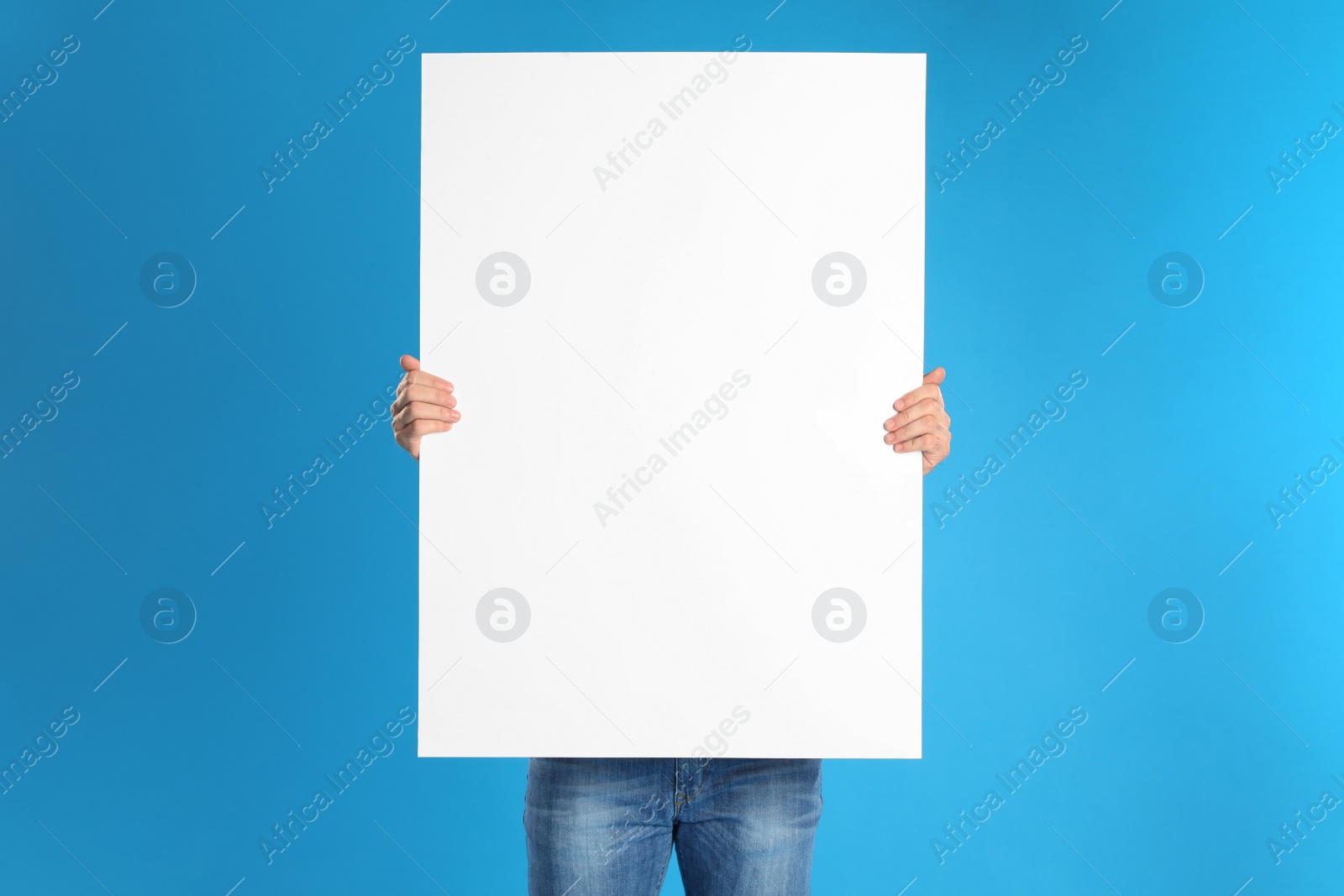 Man holding blank poster on blue background Photo of Man holding blank poster on blue background