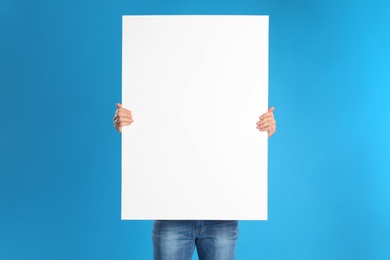 Man holding blank poster on blue background Photo of Man holding blank poster on blue background