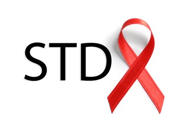 Red awareness ribbon and abbreviation STD on white background, top view Image of Red awareness ribbon and abbreviation STD on white background, top view