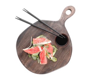 Serving board with fresh crab sticks, cucumber and soy sauce isolated on white Photo of Serving board with fresh crab sticks, cucumber and soy sauce isolated on white