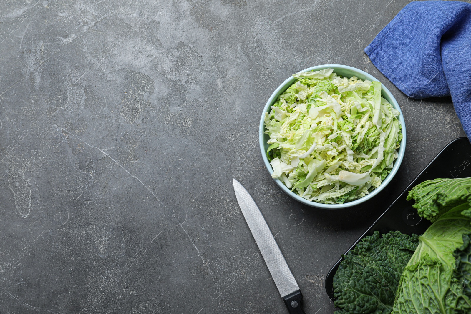 Cut fresh savoy cabbage in bowl on grey table, flat lay. Space for text Photo of Cut fresh savoy cabbage in bowl on grey table, flat lay. Space for text