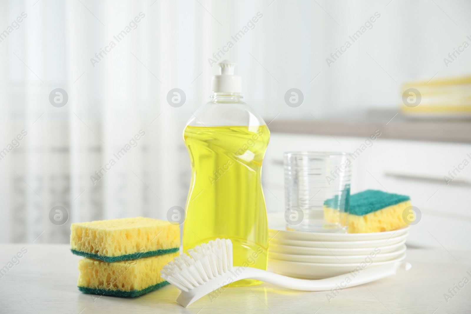 Cleaning supplies for dish washing on table indoors Photo of Cleaning supplies for dish washing on table indoors
