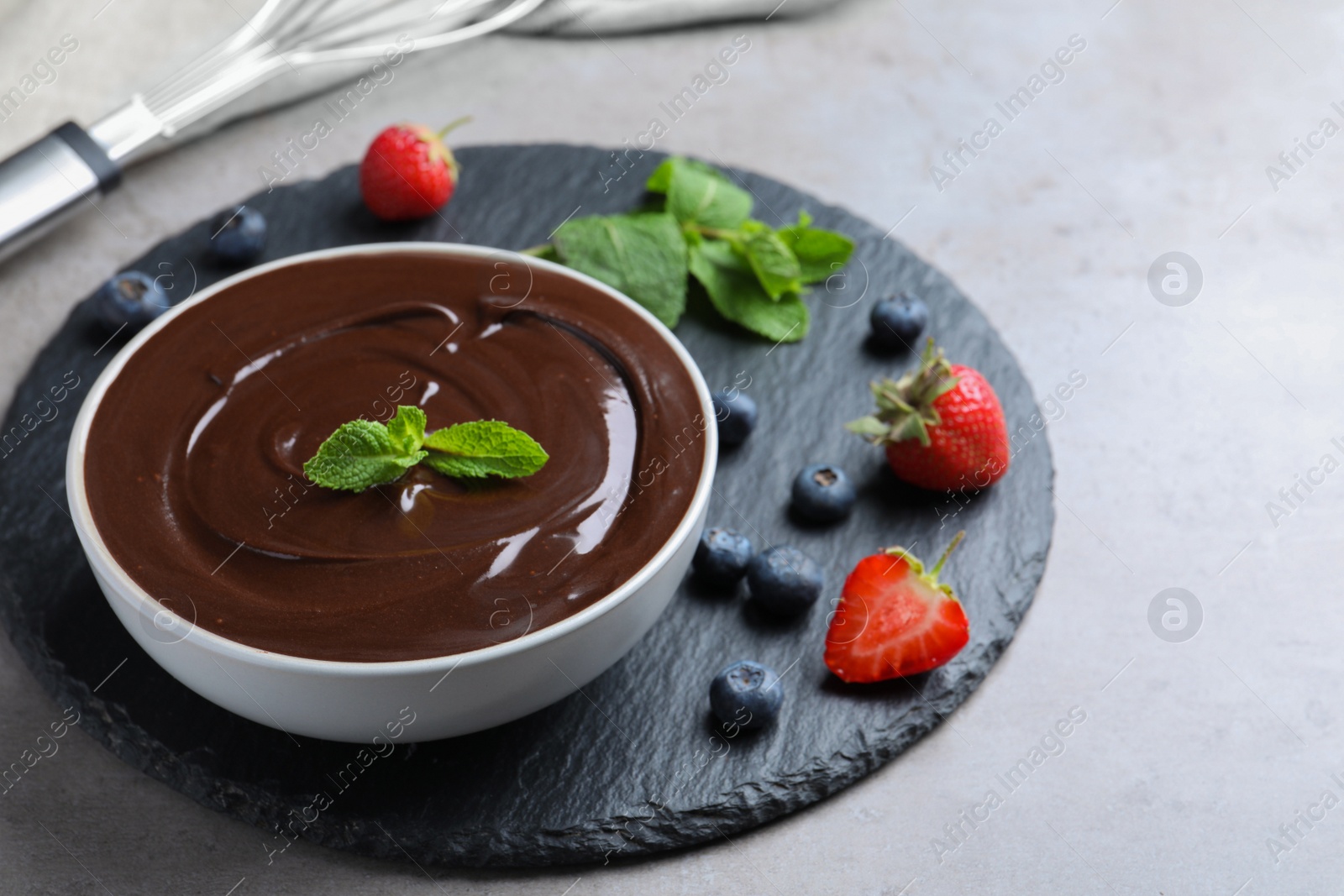 Delicious chocolate cream with berries and mint on grey table, space for text Photo of Delicious chocolate cream with berries and mint on grey table, space for text