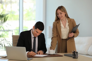 Secretary bringing coffee to her boss in office Photo of Secretary bringing coffee to her boss in office