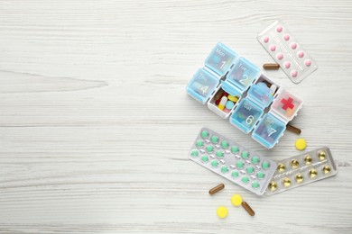 Pill box with medicaments on white wooden table, flat lay. Space for text Photo of Pill box with medicaments on white wooden table, flat lay. Space for text
