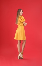 Photo of Young woman wearing stylish yellow dress on red background