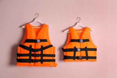 Orange life jackets on pink background. Personal flotation device Photo of Orange life jackets on pink background. Personal flotation device