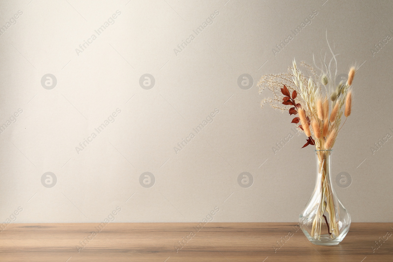 Dried flowers in vase on table against light background. Space for text Photo of Dried flowers in vase on table against light background. Space for text