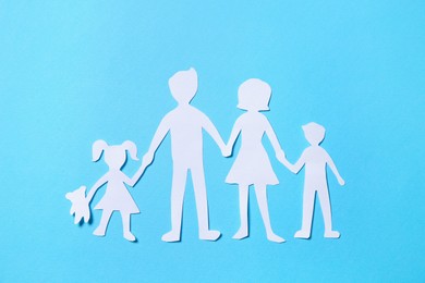 Paper family figures on light blue background, top view Photo of Paper family figures on light blue background, top view