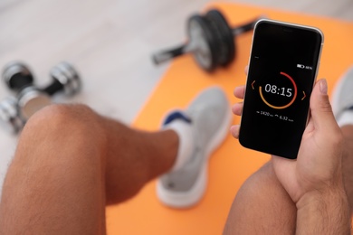 Man using fitness app on smartphone indoors, closeup Photo of Man using fitness app on smartphone indoors, closeup