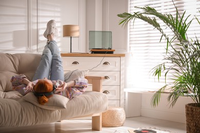 Young woman listening to music with turntable in living room Photo of Young woman listening to music with turntable in living room