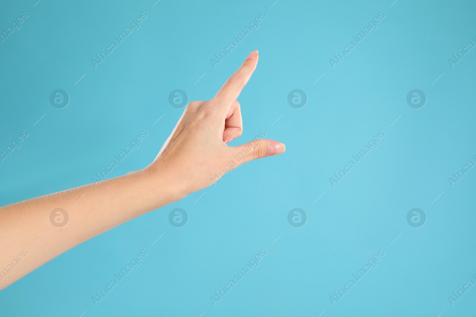 Woman pointing at something on light blue background, closeup. Finger gesture Photo of Woman pointing at something on light blue background, closeup. Finger gesture