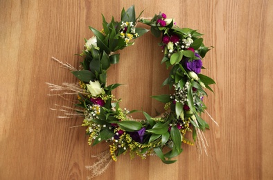 Beautiful wreath made of flowers and leaves on wooden background, top view Photo of Beautiful wreath made of flowers and leaves on wooden background, top view