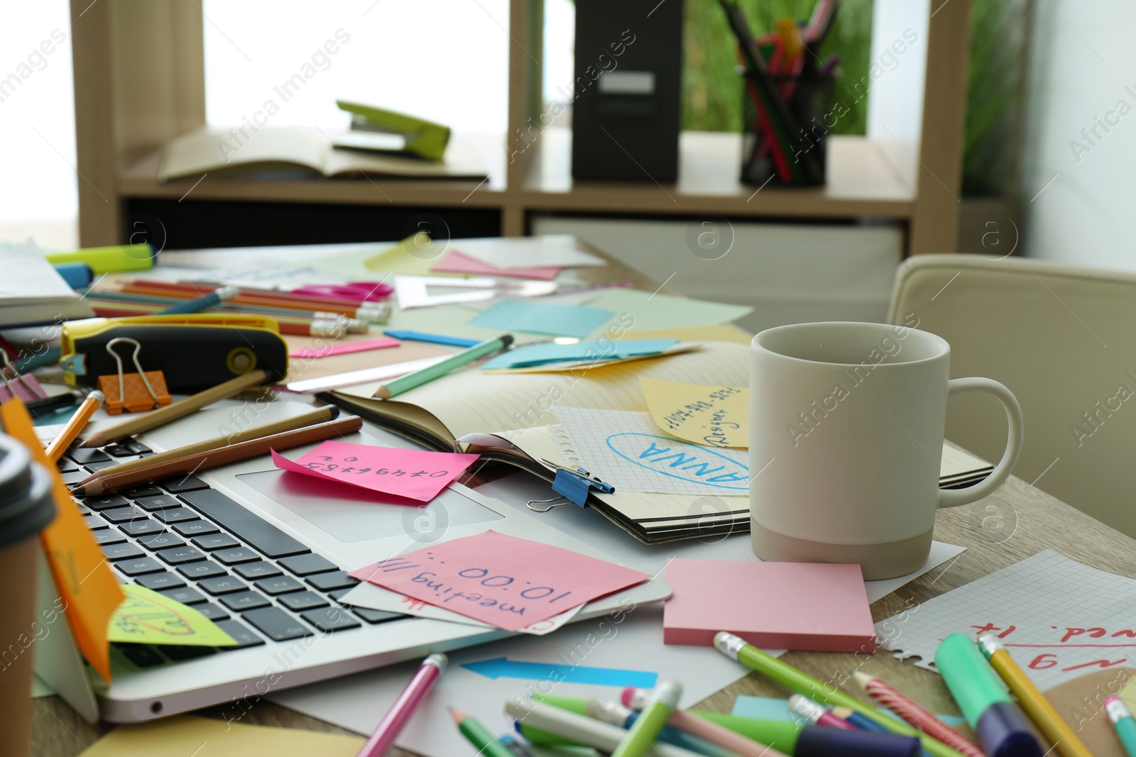 Laptop, notes and office stationery in mess on desk. Overwhelmed with work Photo of Laptop, notes and office stationery in mess on desk. Overwhelmed with work