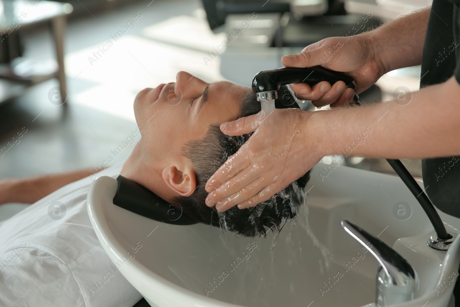 Professional barber washing client's hair at sink in salon, closeup Photo of Professional barber washing client's hair at sink in salon, closeup