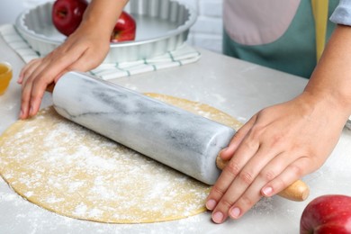Woman rolling dough for apple pie at light grey table, closeup Photo of Woman rolling dough for apple pie at light grey table, closeup