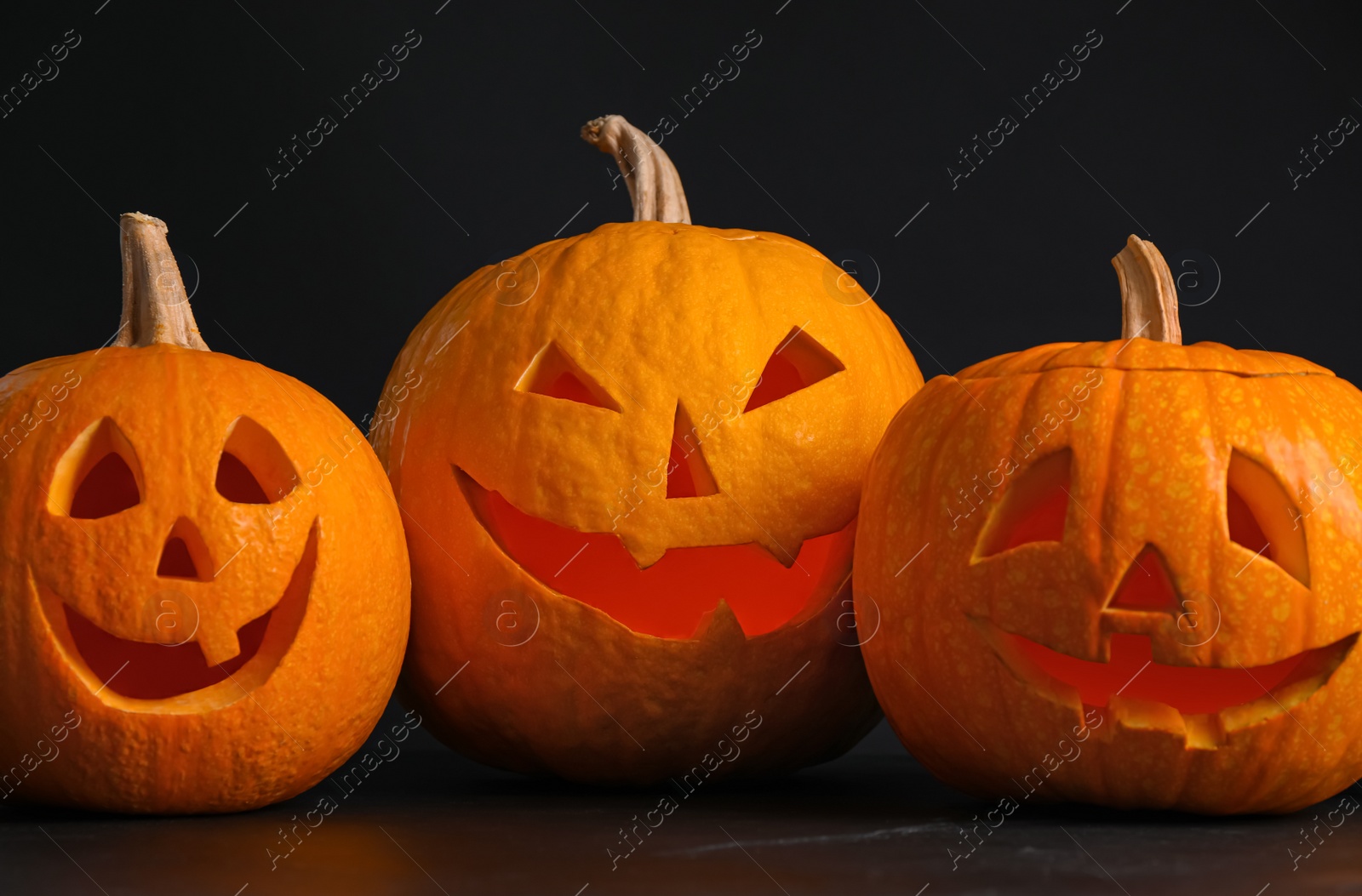 Pumpkins with scary faces on black background. Halloween traditional decor Photo of Pumpkins with scary faces on black background. Halloween traditional decor